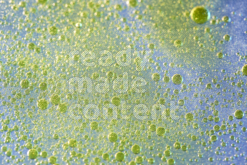 لقطات مقربة لقطرات ألوان مائية صفراء على سطح الزيت على خلفية زرقاء