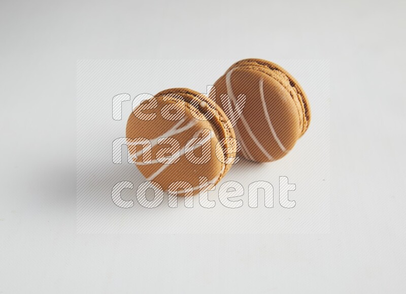 45º Shot of two Brown Irish Cream macarons on white background