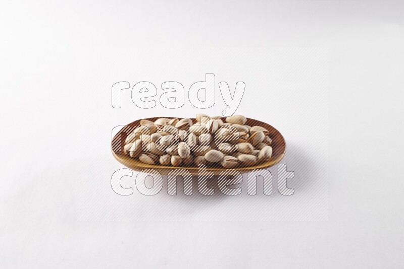 Pistachios in a wooden plate on white background