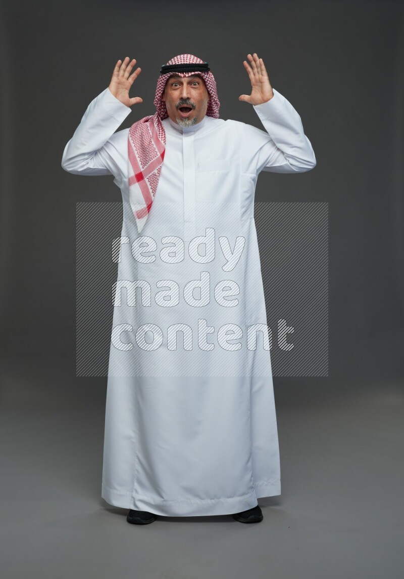 Saudi man with shomag Standing Interacting with the camera on gray background
