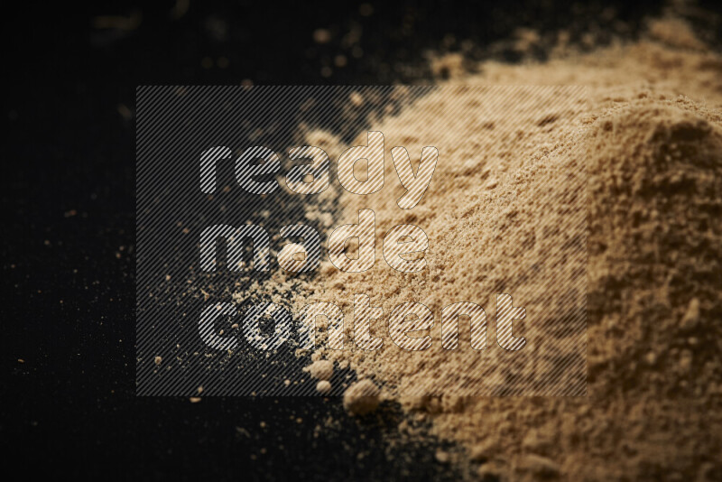 A bunch of ground ginger powder on black background