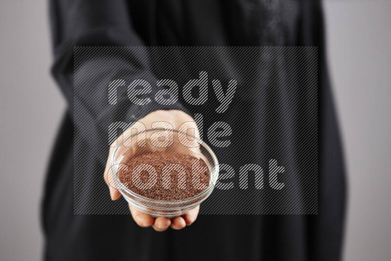 Woman in abaya holding different kinds of spices in different positions