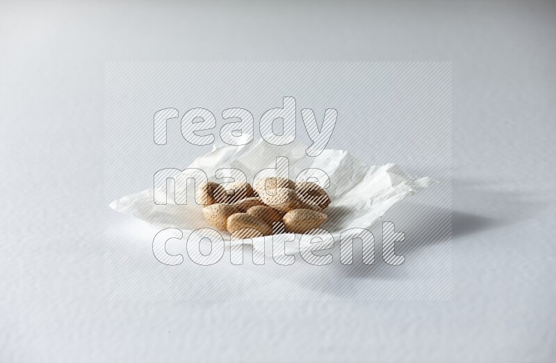 Almonds on a crumpled piece of paper on a white background in different angles