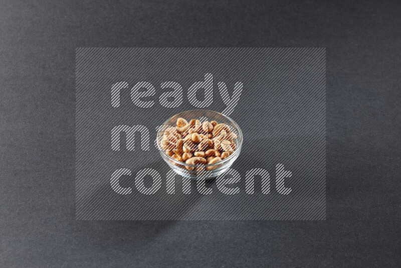 A glass bowl full of cashews on a black background in different angles