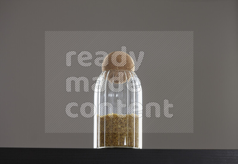 Coarse bulgur in a glass jar on black background