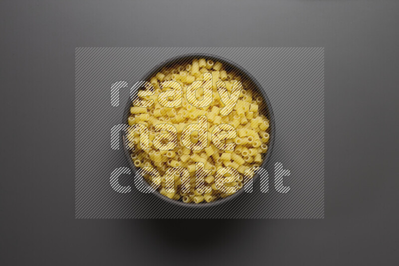 Small rings pasta in a pottery bowl on grey background