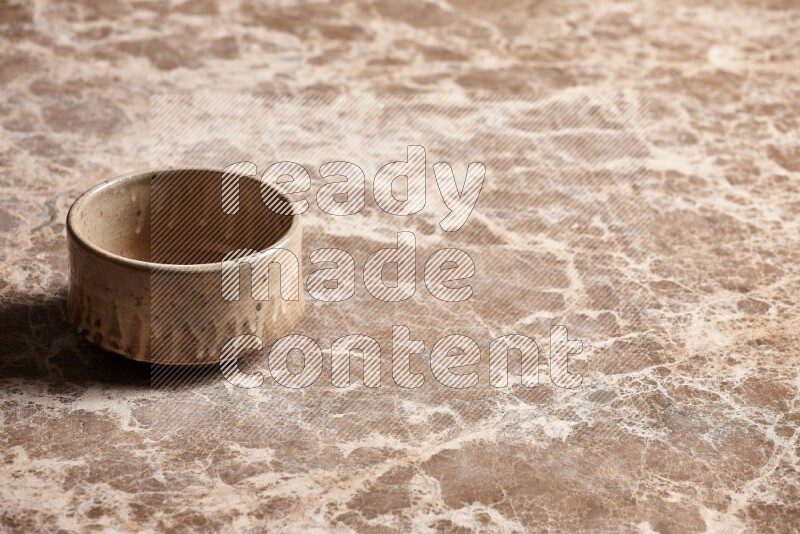 A beige pottery oven bowl on beige marble background