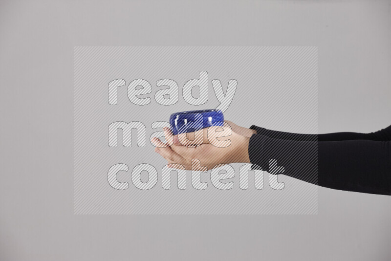 امرأة ترتدي عباءة سوداء تحمل أدوات فخارية مختلفة في أوضاع متعددة