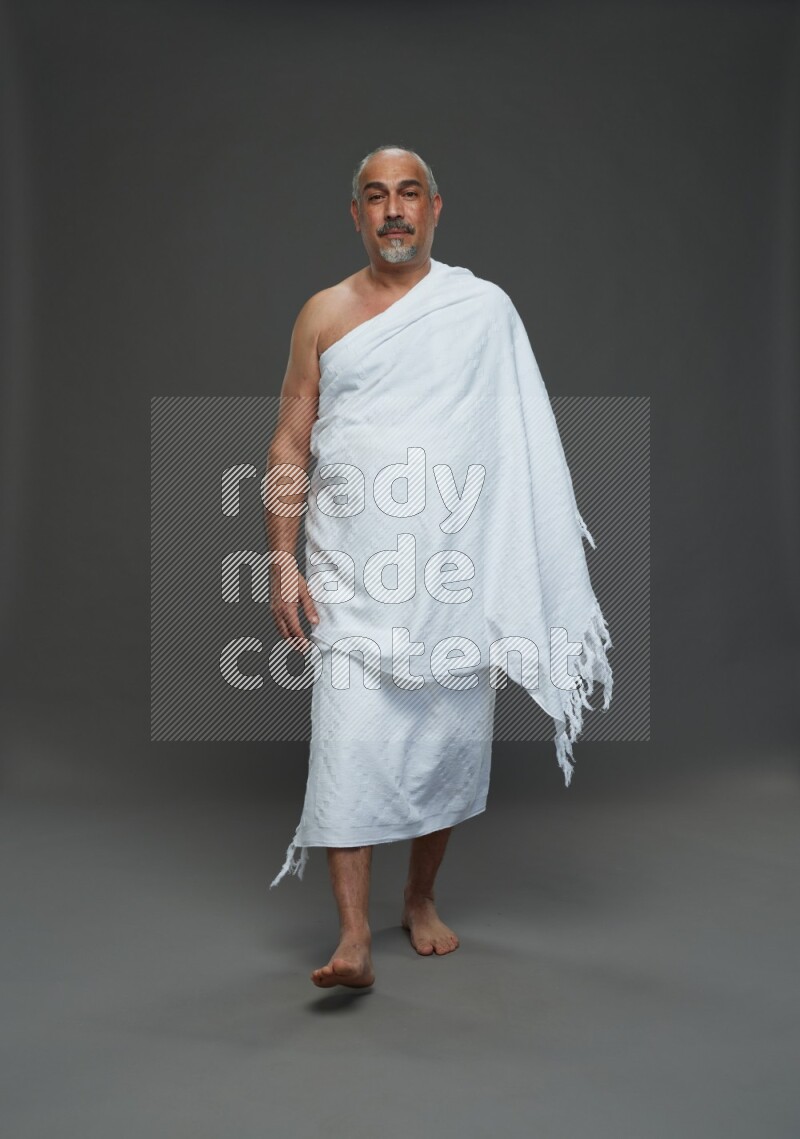 A man wearing Ehram Standing Interacting with the camera on gray background
