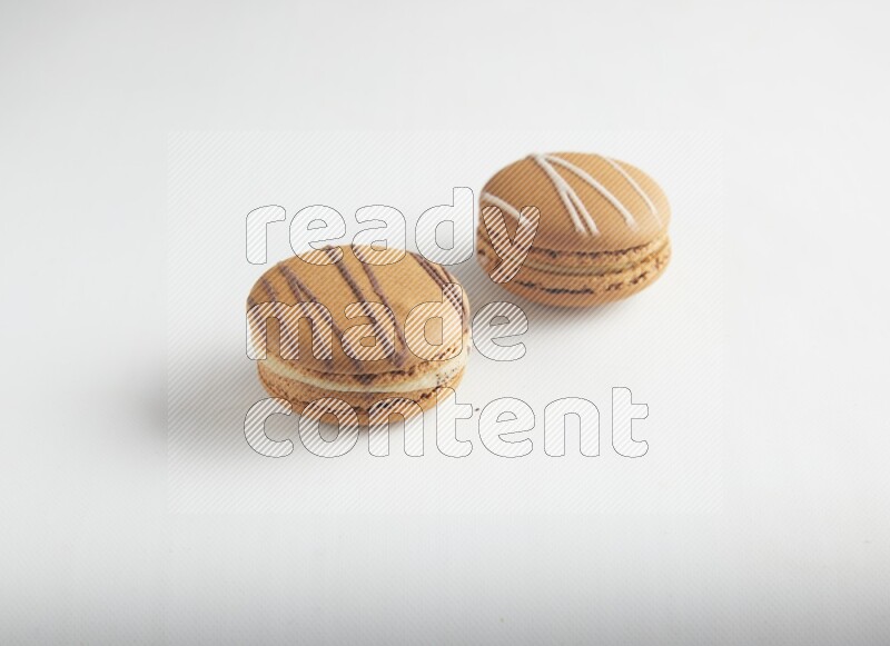 45º Shot of of two assorted Brown Irish Cream, and light brown  Almond Cream macarons on white background