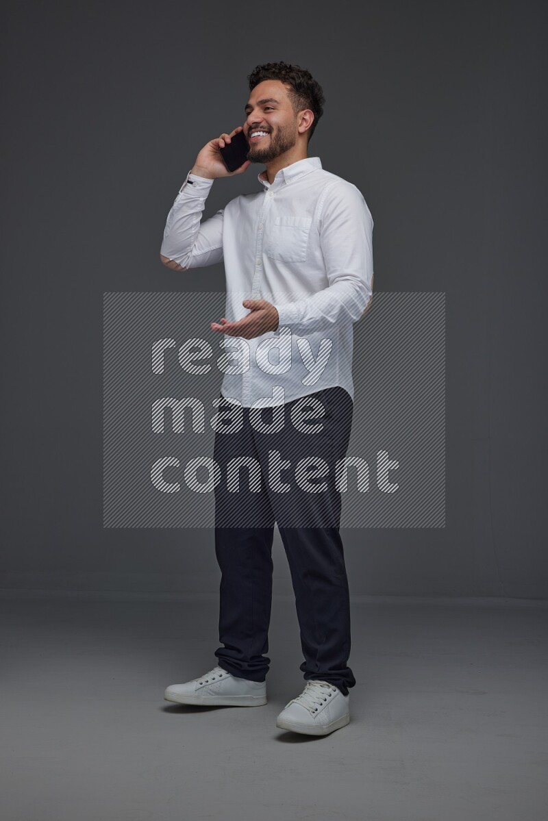 A man wearing smart casual talking in the phone eye level on a gray background