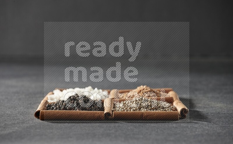 4 squares of cinnamon sticks full of black pepper, white pepper, white salt and mustard seeds on black flooring
