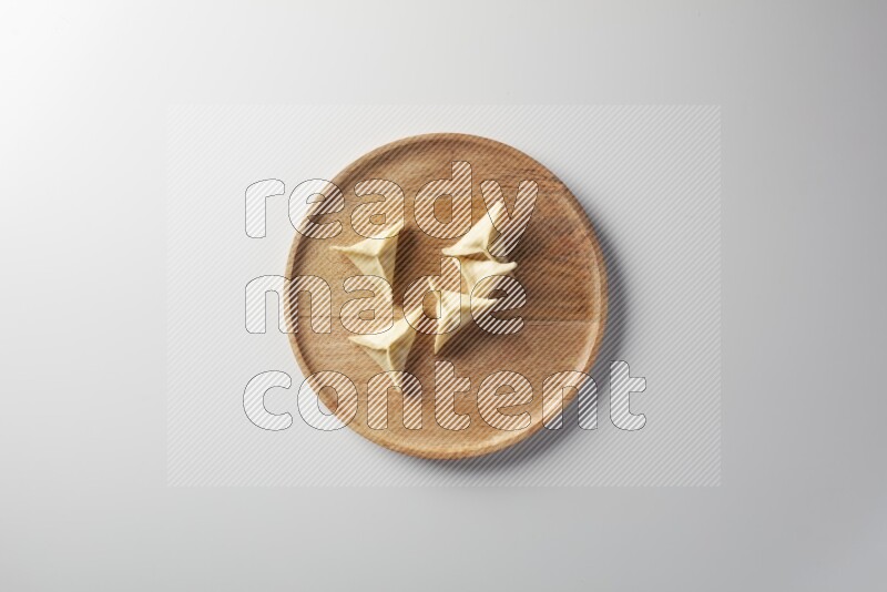 Five Sambosas on a wooden round plate on a white background
