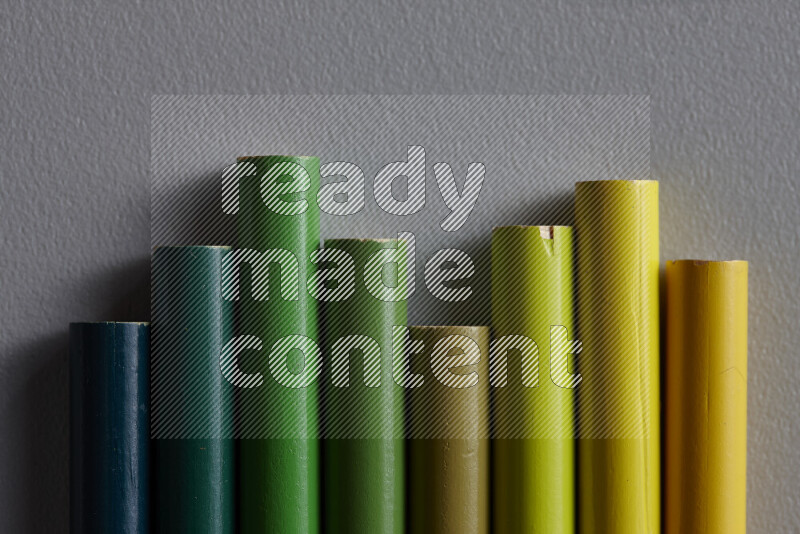 مجموعة من أقلام الرصاص الملونة مرتبة لتعرض تدرجا من الألوان الخضراء علي خلفية رمادية