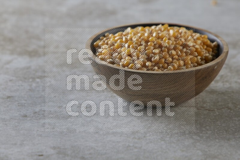 corn kernel in a wooden bowl on a grey textured countertop