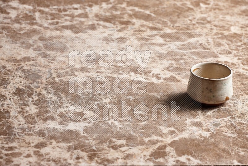 A beige pottery bowl on beige marble background