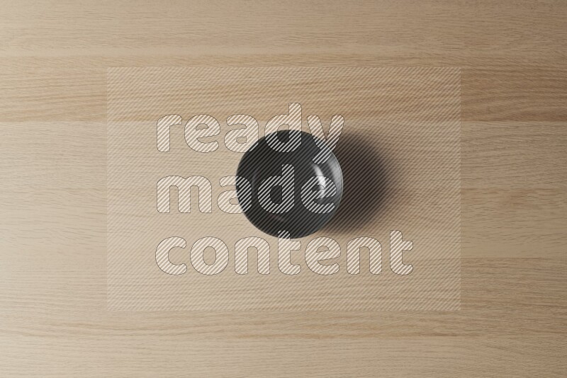 A black ceramic bowl on light wooden background