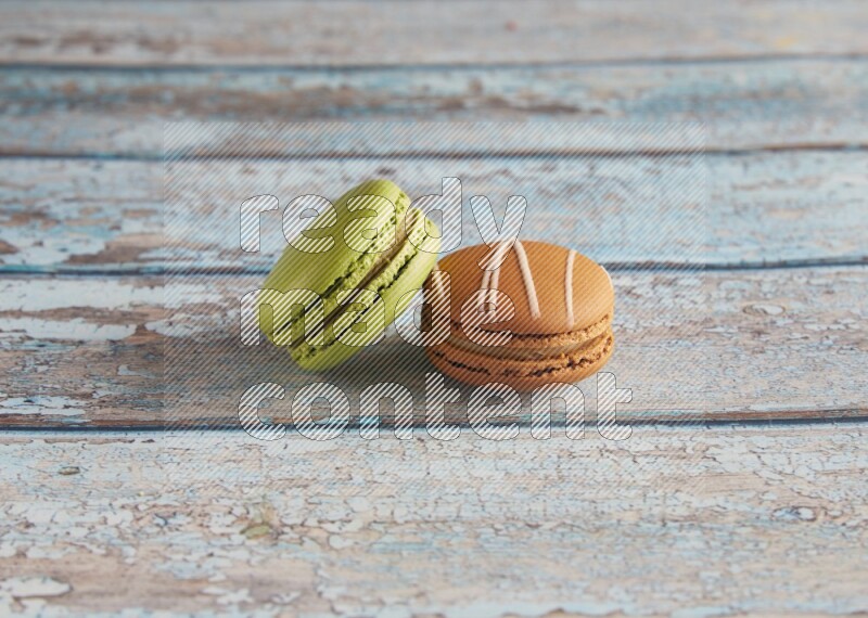 45º Shot of of two assorted Brown Irish Cream, and Green Pistachio macarons  on light blue background