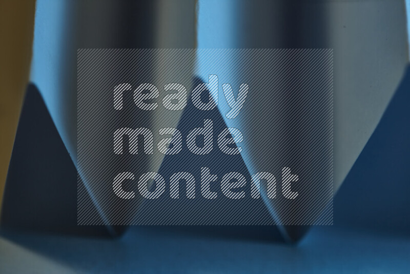 A close-up abstract image showing sharp geometric paper folds in blue gradients and warm tones