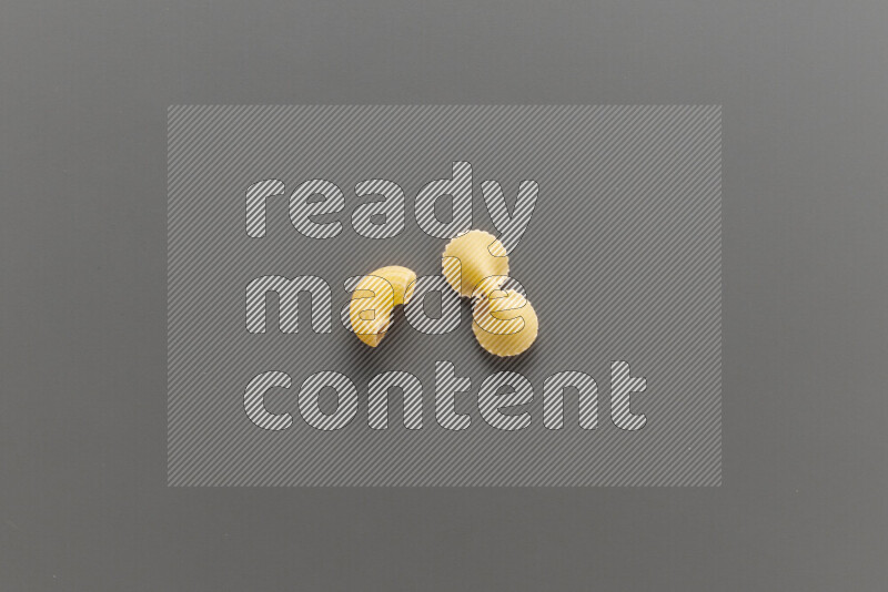 Elbow pasta with other types of pasta on grey background