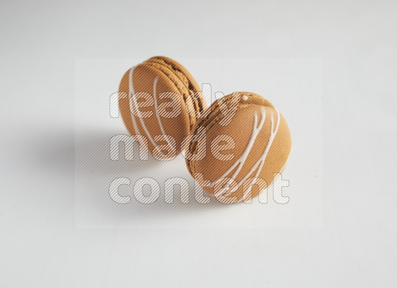 45º Shot of two Brown Irish Cream macarons on white background