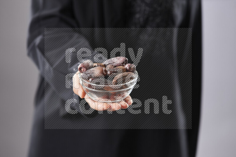 امرأة ترتدي عباءة تحمل أنواع مختلفة من التمر في أوضاع متعددة