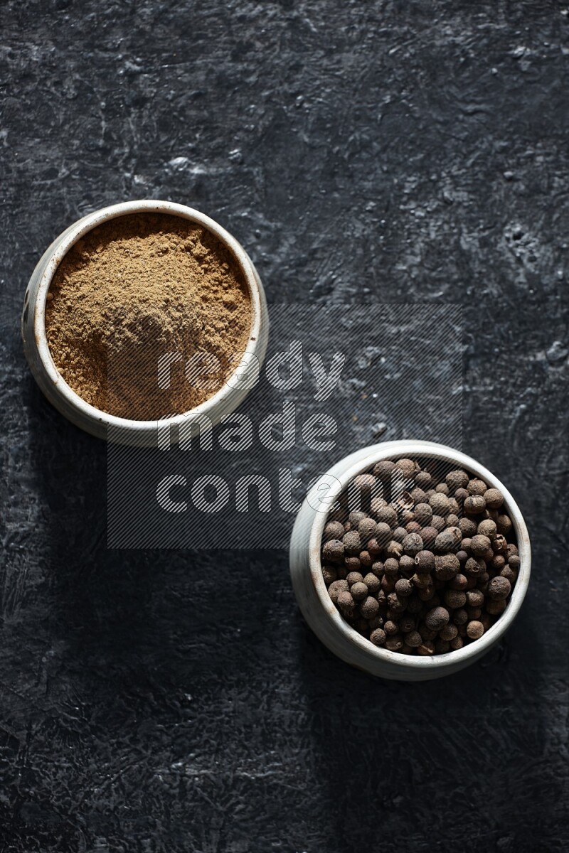 وعاءان بيج، أحدهما ممتلئ ببودرة بهار الفلفل الحلو والآخر بالحبوب على خلفية سوداء