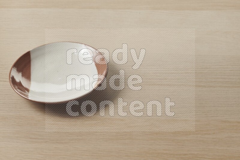 A multicolored pottery plate on light wooden background