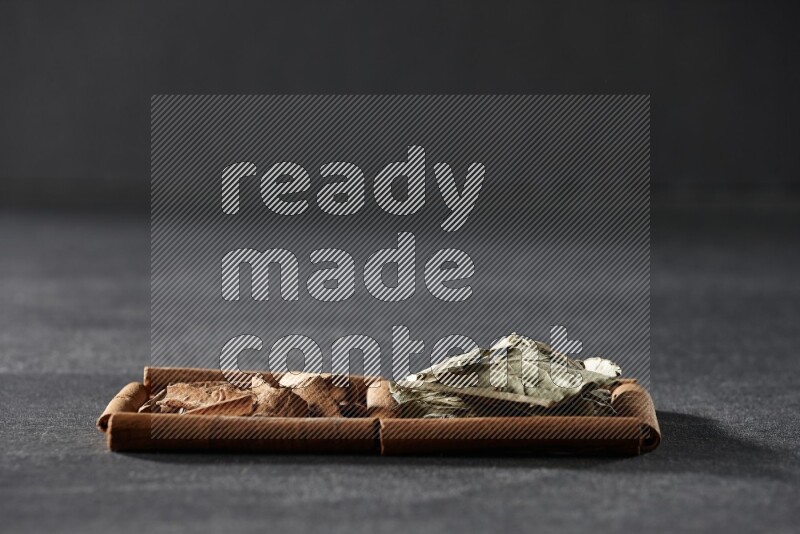 2 squares of cinnamon sticks full of cinnamon and bay laurel leaves on black flooring