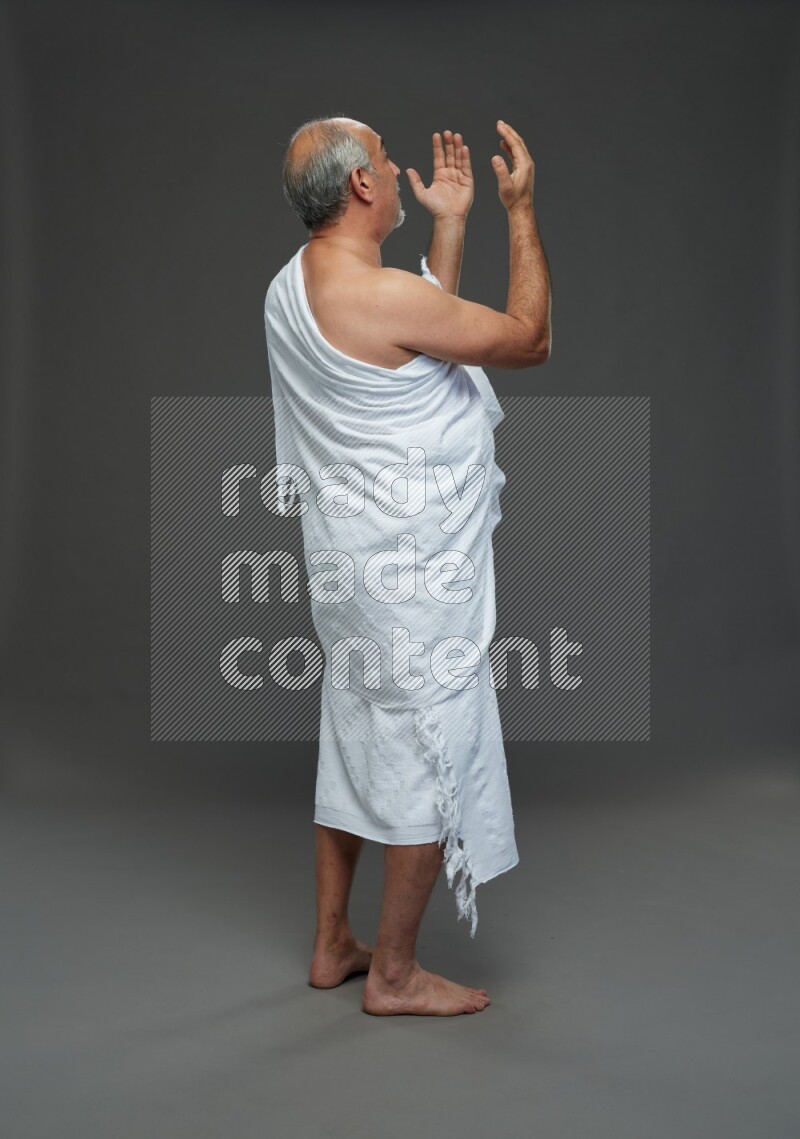 A man wearing Ehram Standing dua'a on gray background