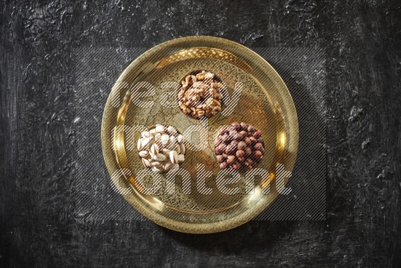 Nuts in metal bowls on a tray in a dark setup