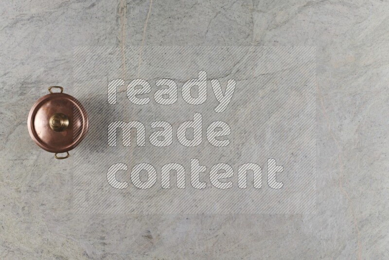 A small copper pot on grey marble background