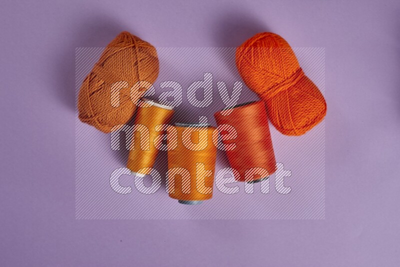 An orange collection of sewing and tailoring tools arranged on a purple background