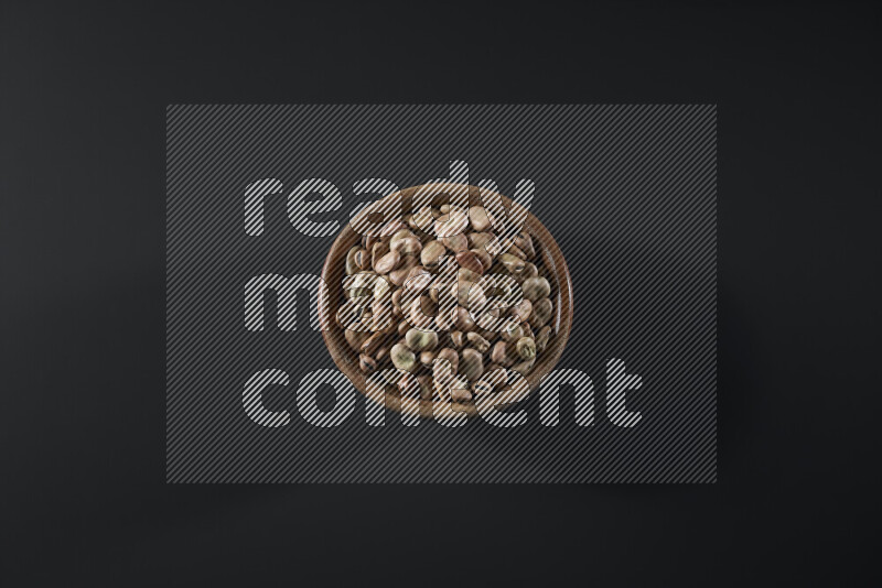 Fava beans in a wooden bowl on grey background
