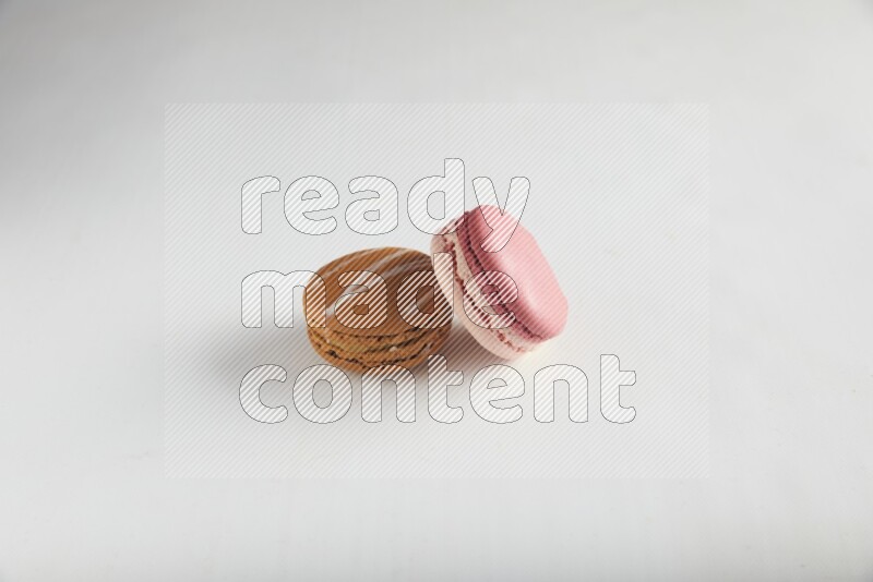 45º Shot of of two assorted Brown Irish Cream, and Pink Litchi Raspberry macarons on white background