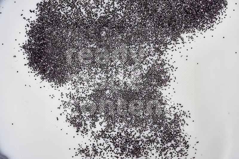 A close-up of sparkling purple glitter scattered on swirling green and white background