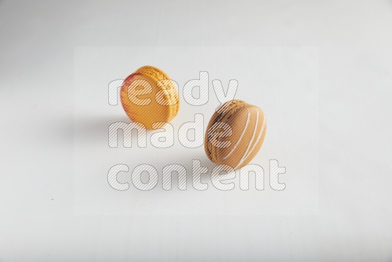 45º Shot of of two assorted Brown Irish Cream, and Orange Exotic macarons on white background