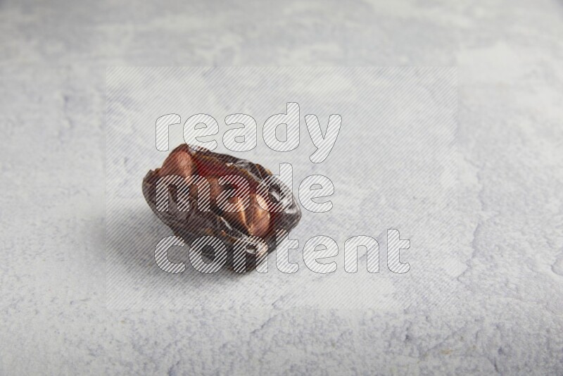 hazelnuts stuffed madjoul date on a light grey background