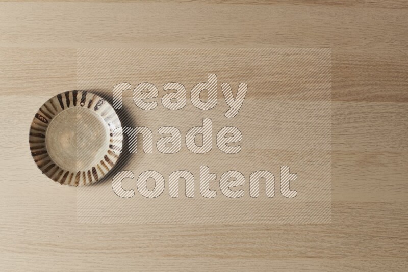 A multicolored pottery plate on light wooden background