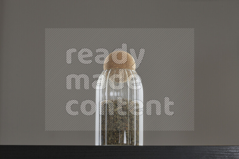 Dried basil in a glass jar on black background