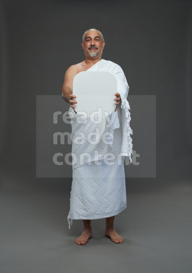 A man wearing Ehram Standing holding social media sign on gray background
