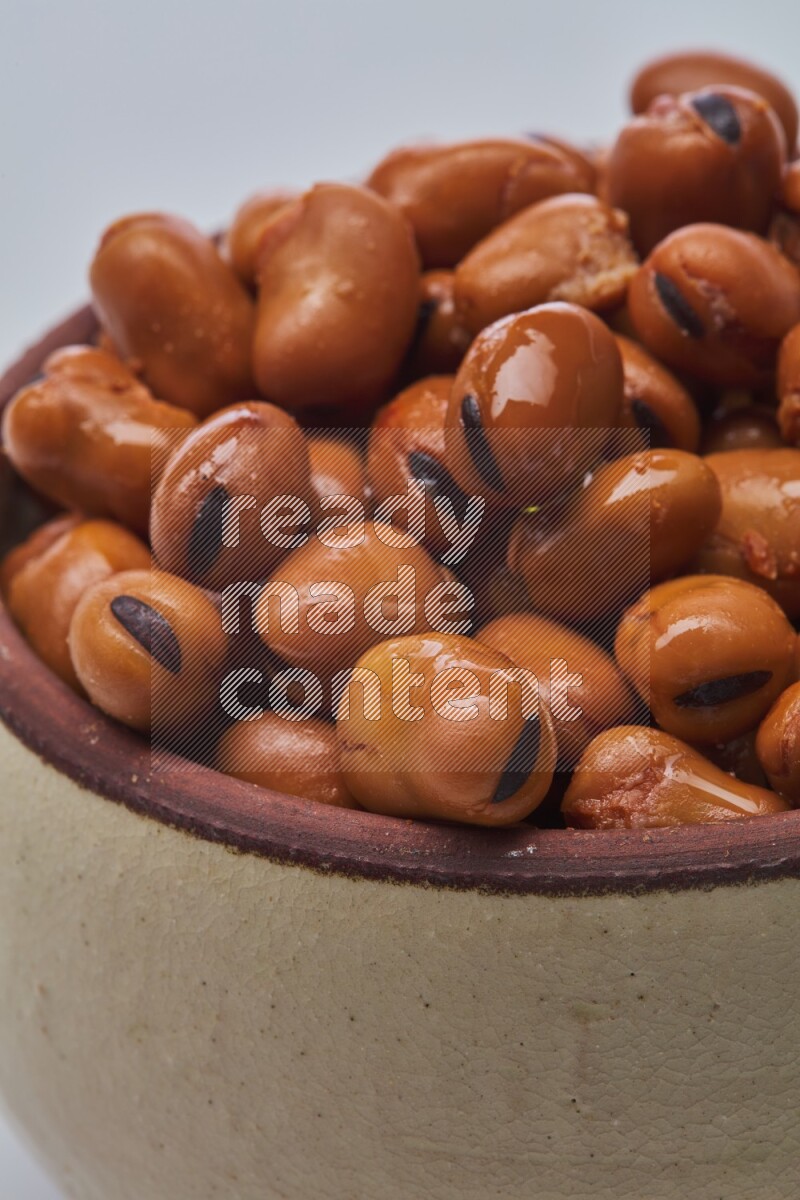 Close up shot of cooked fava beans (foul) in a container on white background