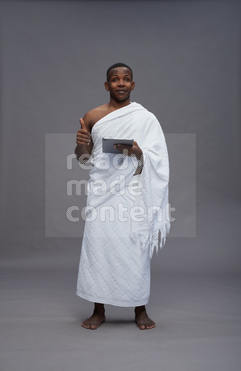 A man wearing Ehram Standing working on tablet on gray background