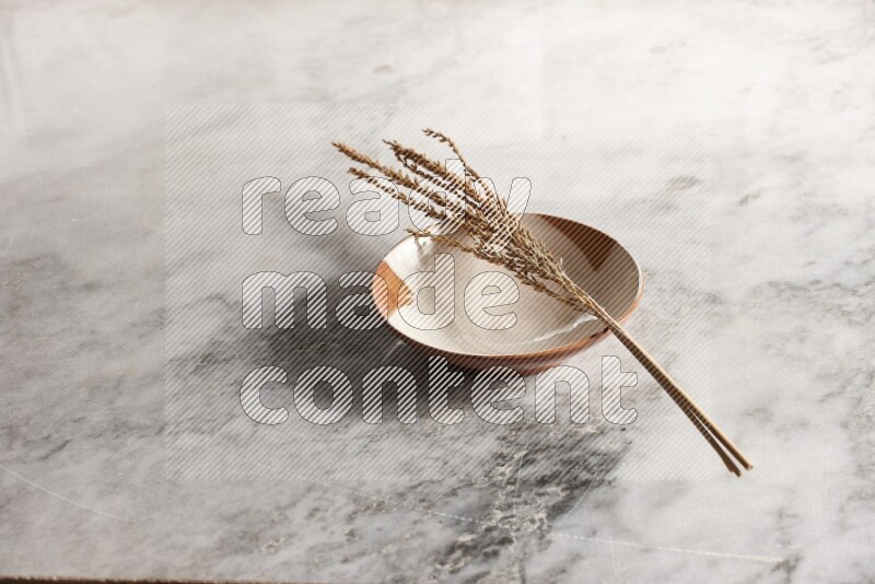 Wheat stalks on multicolored pottery plate on grey marble background