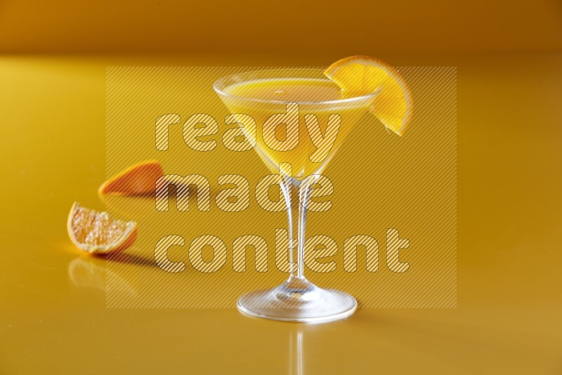 glass of orange juice with orange slice on yellow background