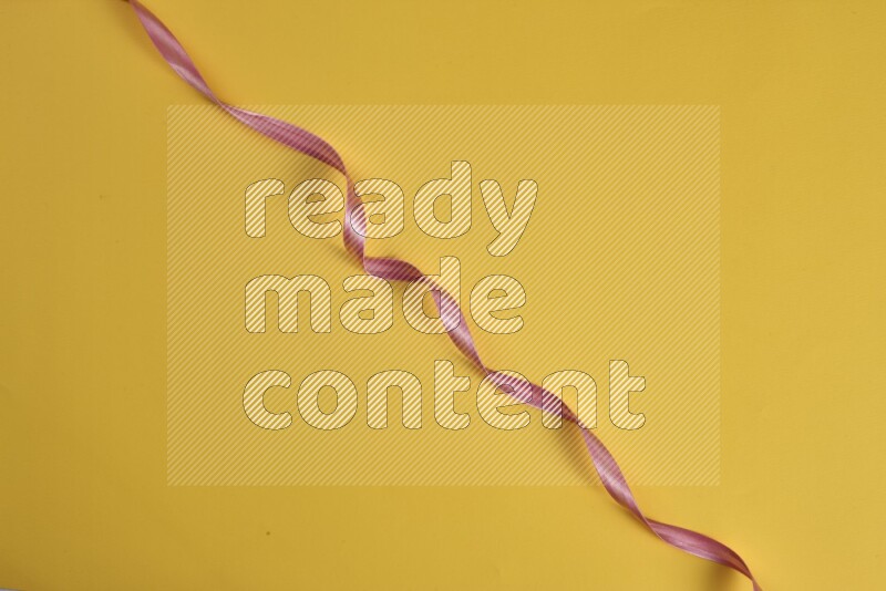 A pink collection of sewing and tailoring tools arranged on a yellow background