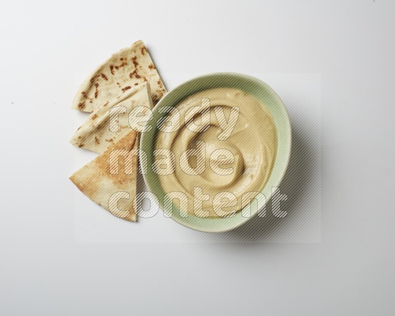 plain Hummus in a green plate on a white background
