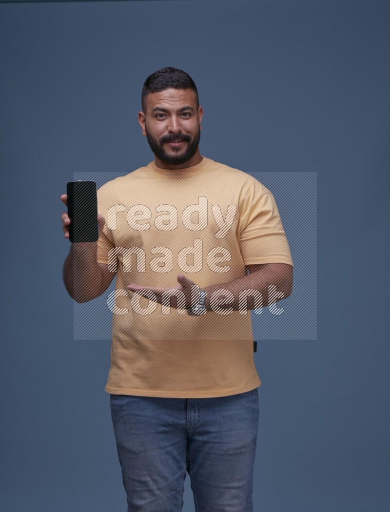 A man Showing His Smart Phone on Blue Background wearing Orange T-shirt