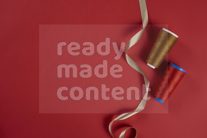 مجموعة من أدوات الخياطة والتفصيل بنية وحمراء اللون على خلفية حمراء