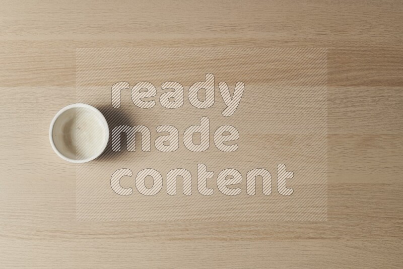 A white pottery bowl on light wooden background